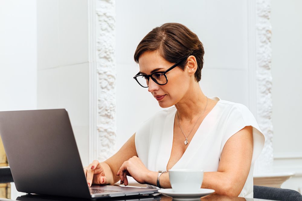 Woman typing on laptop while sitting at table in her apartment