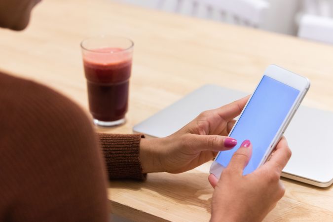 Anonymous Black woman using mobile phone in cafe