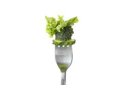 Fork with salad, cucumber and broccoli isolated on blank background