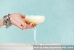 Woman reaching for cocktail glass of eggnog 5QO3Gb