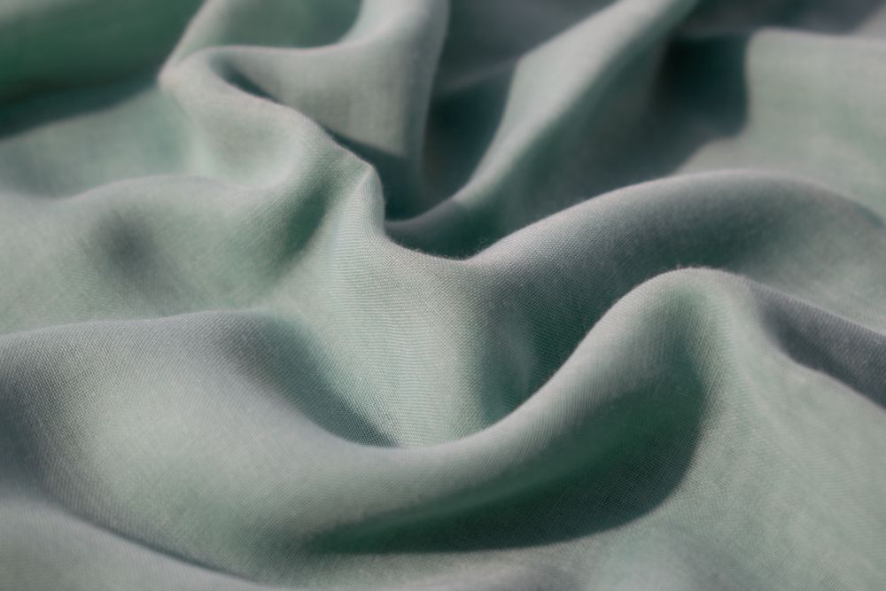 Nude green fabric wavy crumpled background texture with copy space.