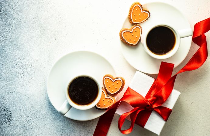 Top view of two coffees on counter with iced cookies and heart candles