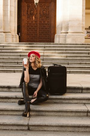 Cheerful tourist drinking on steps