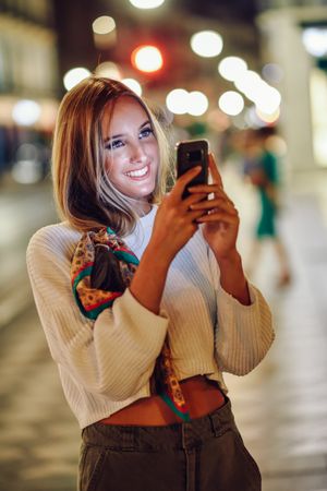 Chic smiling woman with scarf in hair taking photo with phone