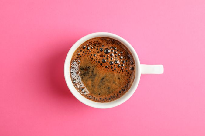 Cup of coffee on color background, space for text