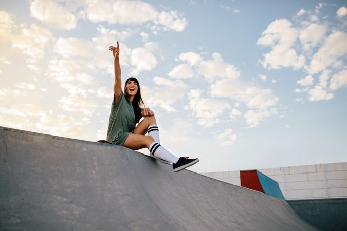 Female skateboarder sitting on a ramp in skate park having fun