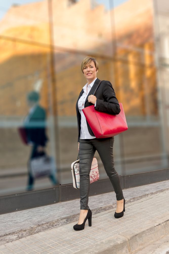 Trendy happy businesswoman walking down street in heels
