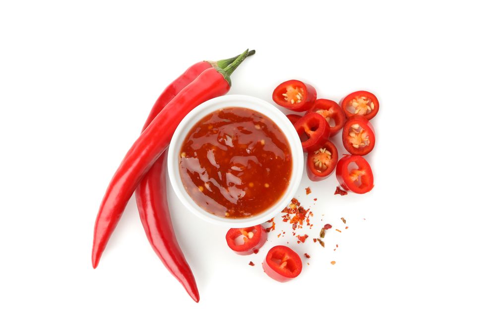 Chilli pepper and bowl of sauce isolated on plain background