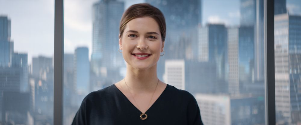 Close Up Portrait of White Businesswoman Posing Next to Window in Big City Office with Skyscrapers.
