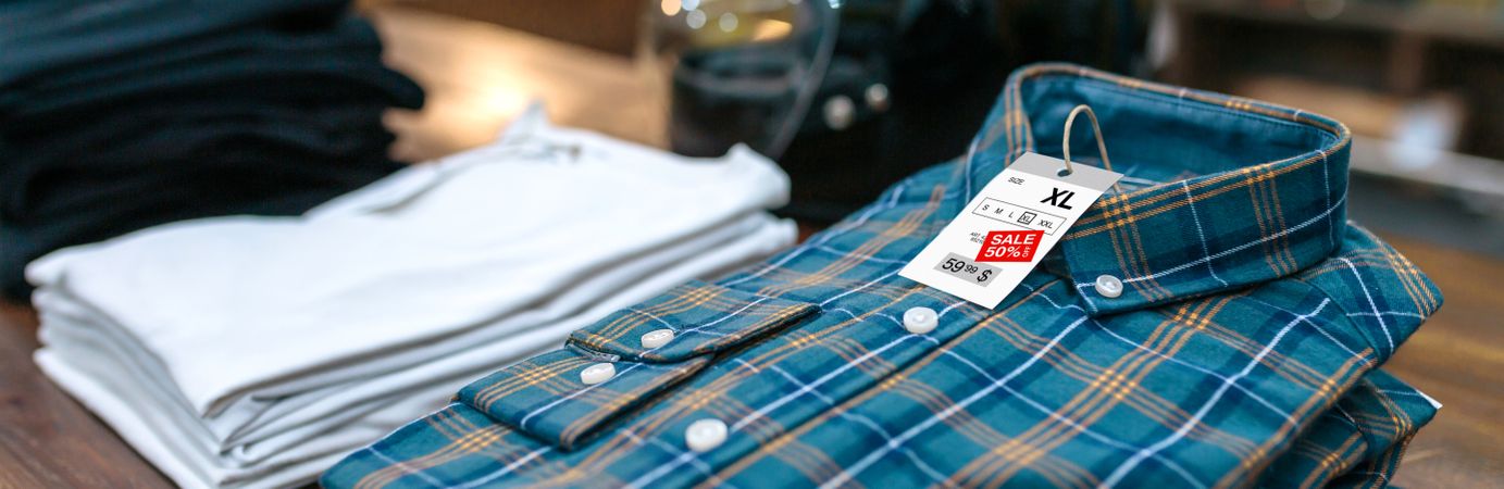 Detail of label with promotion price over a blue plaid shirt on shop with industrial style