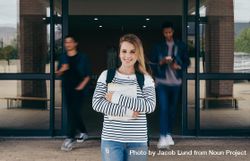 Young woman standing in college with students walking in background in motion blur 0Lr2R4