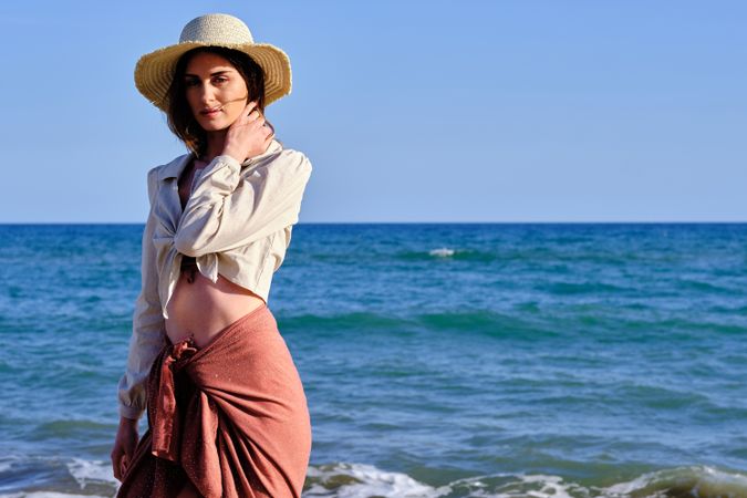 A fashion model with a hat at the beach before sunset