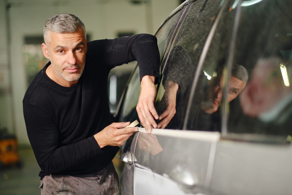 Mechanic putting protective tape on car