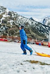 Boy with sleigh walking against mountains