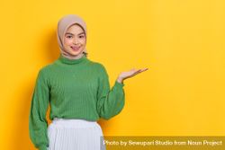 Smiling woman in headscarf with her palm up towards copy space 0P8dO0