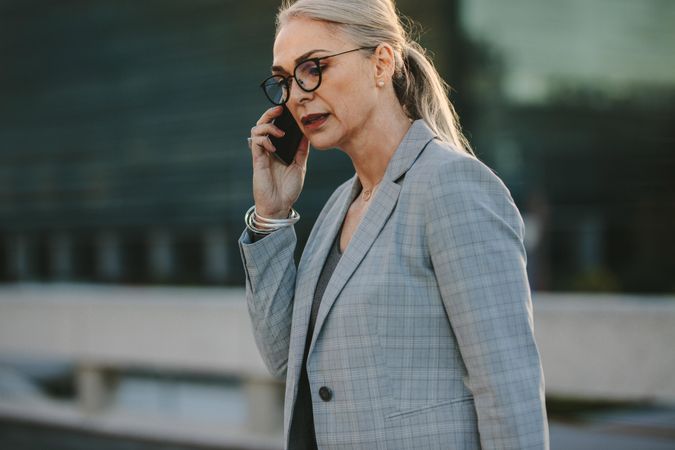 Female in business suit walking outdoors talking on mobile phone