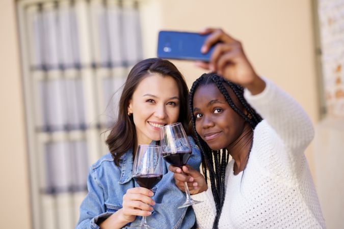 Female friends at an outdoor restaurant with red wine taking a self portrait
