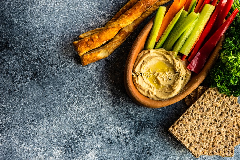 Top view of hummus dish in bowl on grey counter with copy space