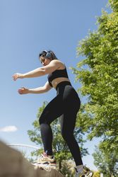 A young woman performs exercises to strengthen legs and buttocks, in a bench, during a sunny day, Zaragoza, Spain