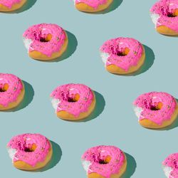 Patter of pink glazed donut on blue pastel background
