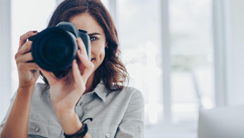 Portrait of freelance photographer holding digital camera in front of her face