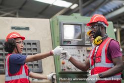 Two employees bumping fist in factory 4d6AA0