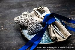 Blue ribbon wrapping cutlery with heart decorations on plate 4BaawM