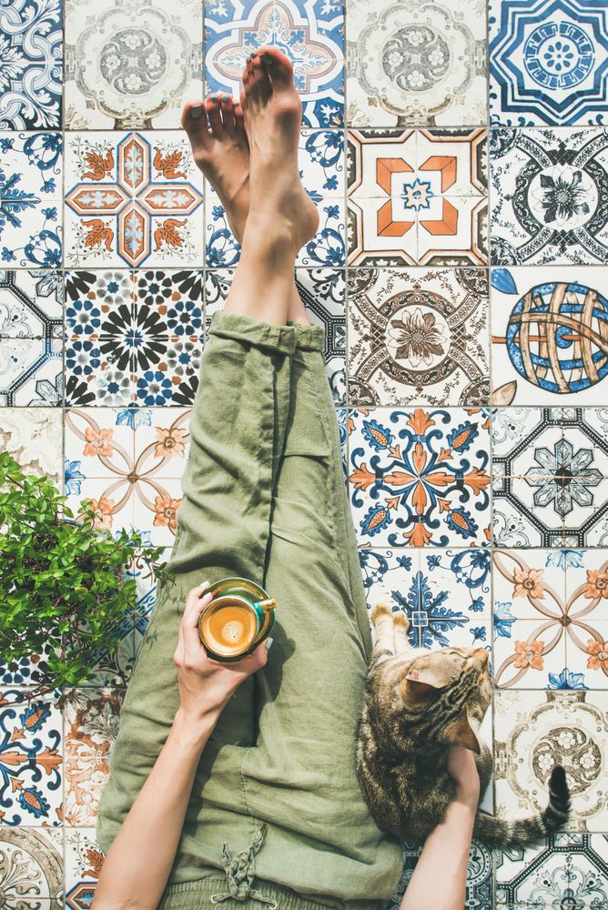 Woman on tiled terrace with coffee and cat