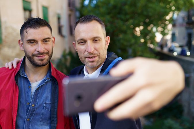 Two serious men taking selfie outside