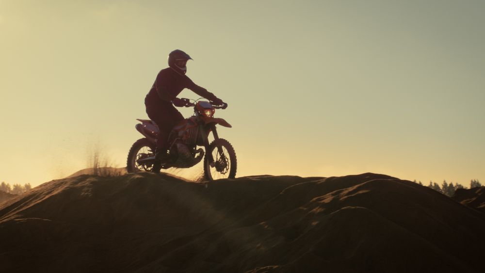 Professional Motocross Motorcycle Rider Drives Over the Dune and Further Down the Off-Road Track.