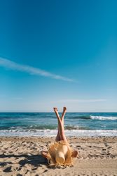 Woman in big hat lying on sandy beach