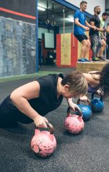 Sportswomen doing push-ups with kettlebells