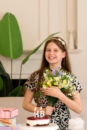 Girl standing by birthday cake with flowers