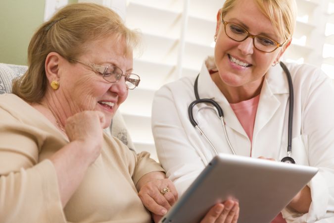 Doctor or Nurse Talking to Older Woman with Touch Pad