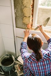 Bricklayer laying tile on the wall with spatula
