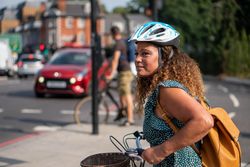 Happy Black woman looking around street on her bike in city streets 42KXgb