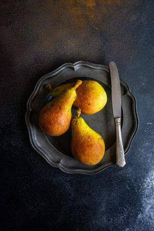 Three pears on plate with knife