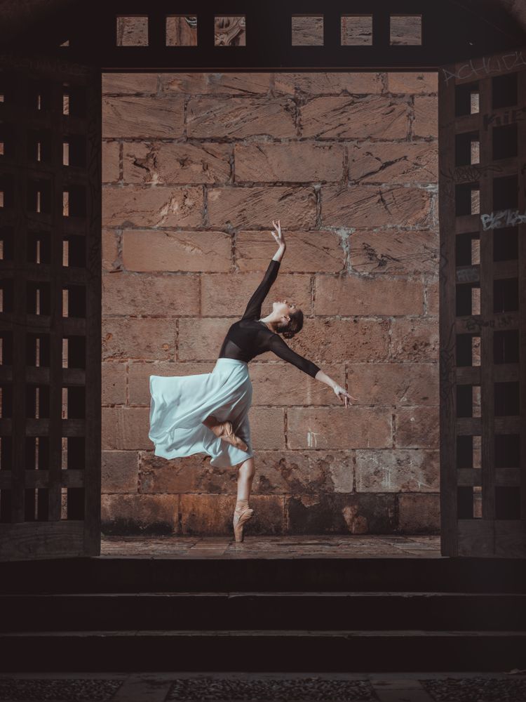 Graceful ballerina dancing in doorway in ancient building