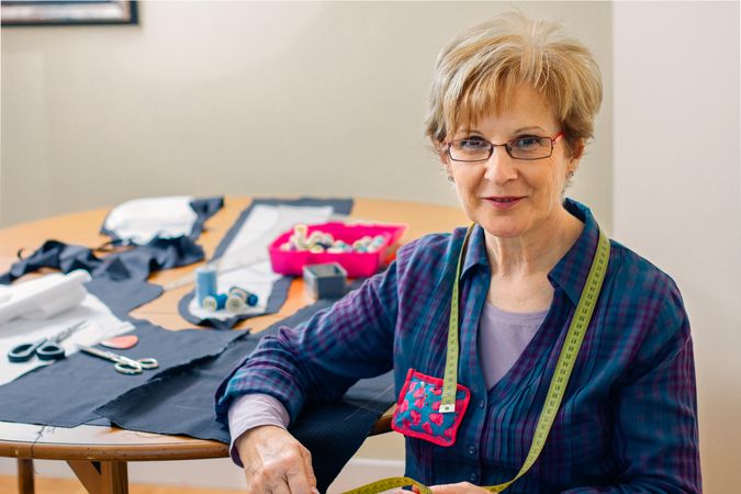 Mature dressmaker posing with sewing materials
