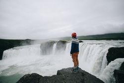 Male standing on rocky cliff over waterfall
