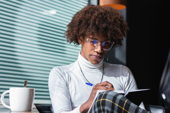 Concentrated trendy young Black guy doing assignment in cafe