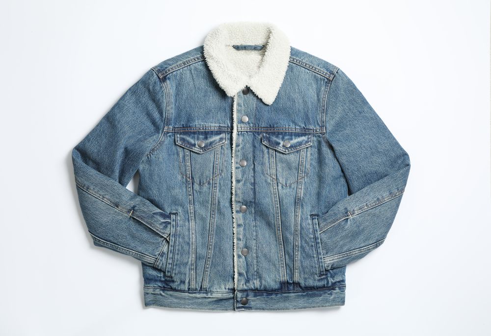 Denim jacket on light background, top view