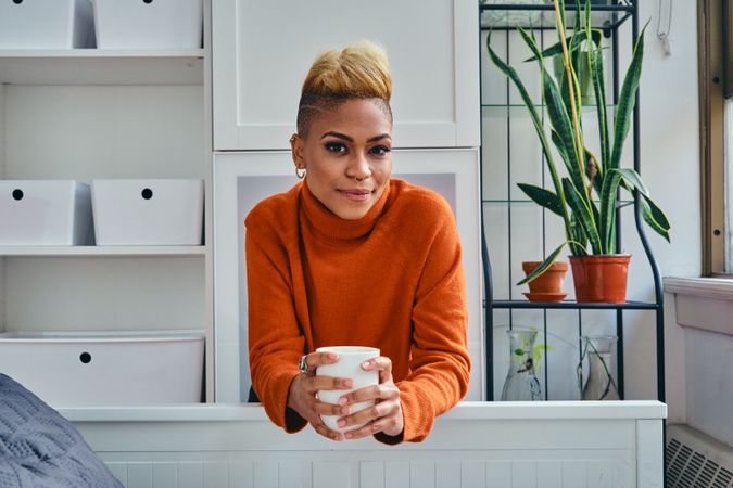 Calm Black woman with a cup of coffee in a bright modern home