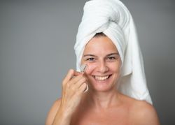 Cheerful female massaging face with jade roller