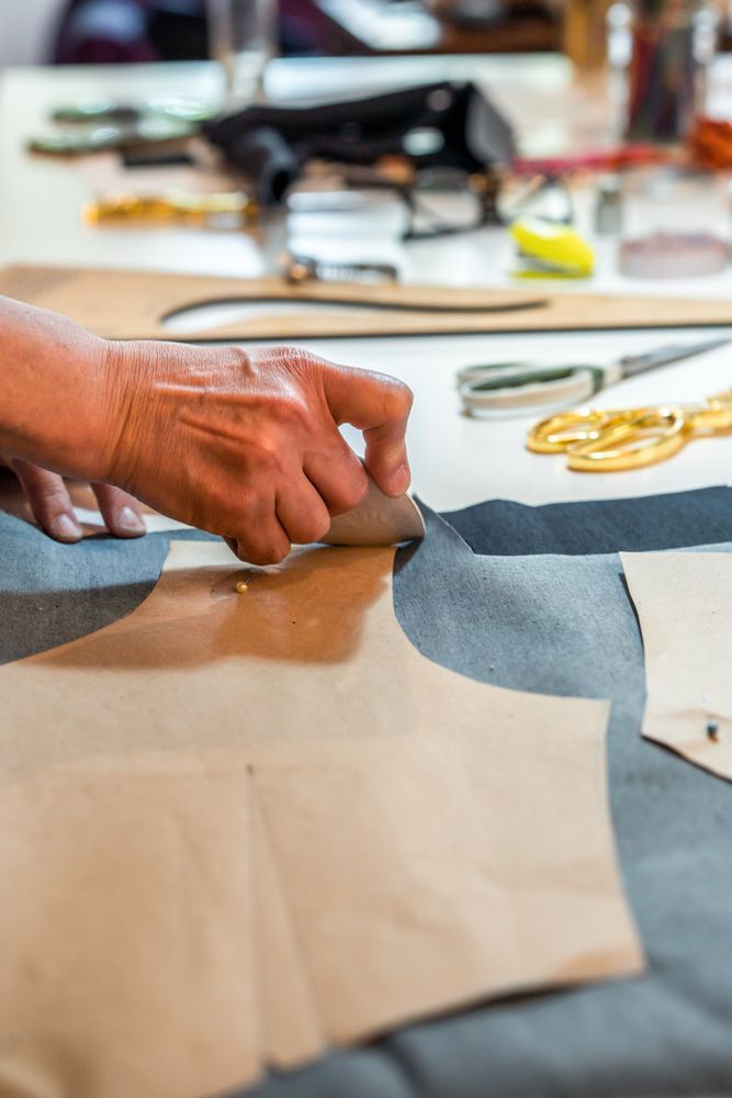 Fashion designer outlining fashion patterns with a tailor's chalk. Vertical shot.