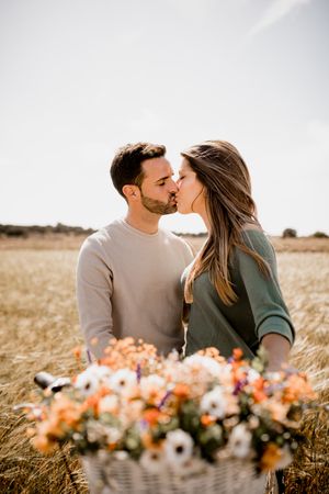Sincere lovers posing by bicycle on rye field