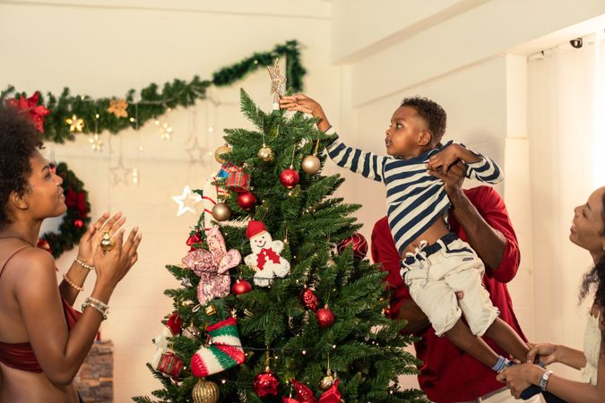 Black family is decorating a Christmas tree together.