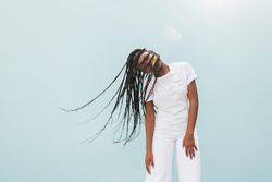 Smiling Black woman with long braids playing with her hair