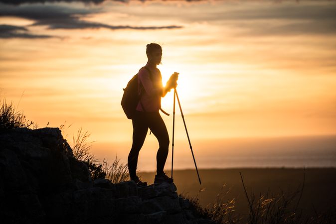 Silhouette of person with walking sticks in sunset