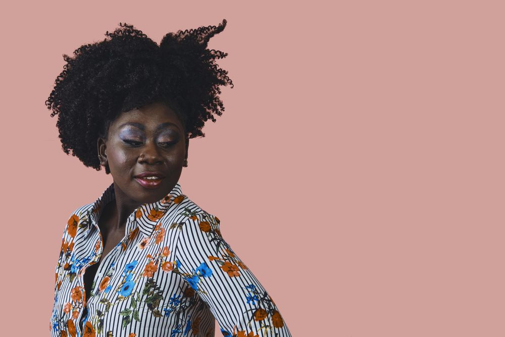 Studio shot of Black woman in floral print shirt looking down